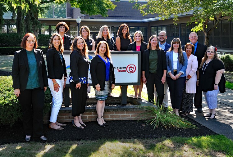 SST8 staff standing around the Summit ESC and SST8 sign at our office